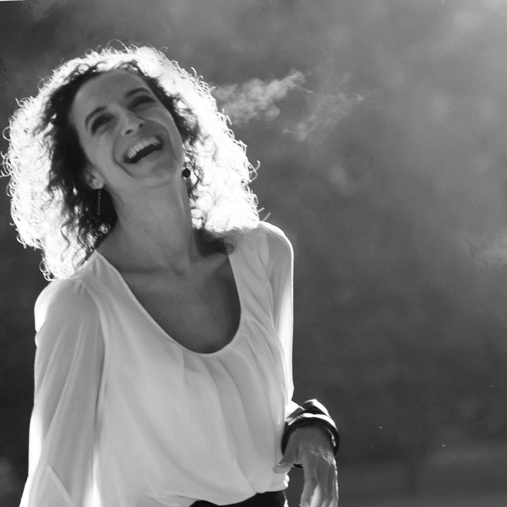 Žena s kučeravými vlasmi a úsmevom na tvári.